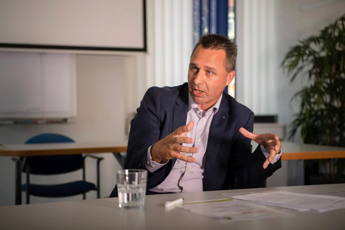 Stefan Lenz sitzt an einem Tisch und gestikuliert. 